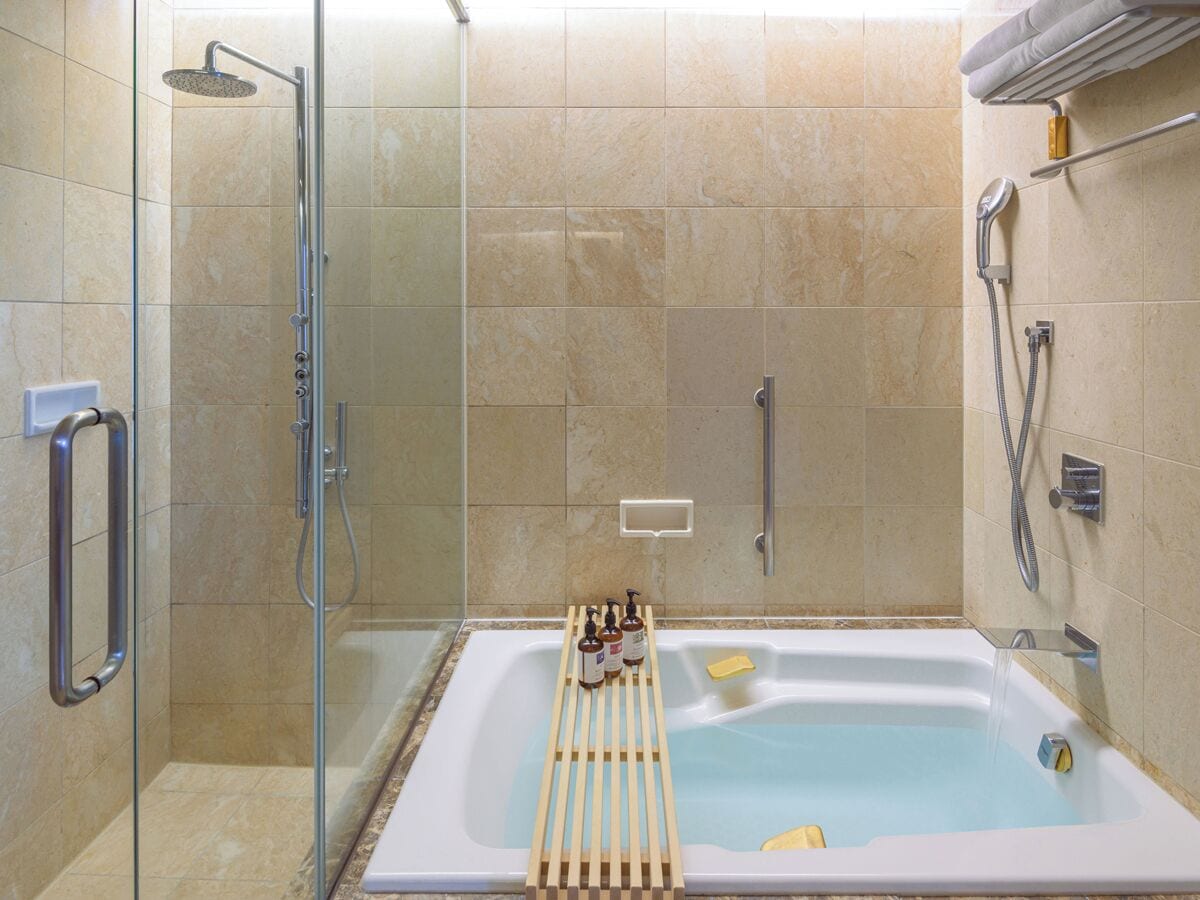 A bathroom with a glass-enclosed shower, a bathtub, and a towel rack.