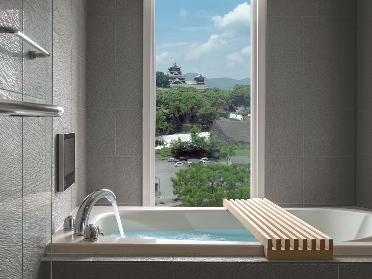 A modern bathroom with a bathtub, a window with a view of traditional architecture, and a towel rack.