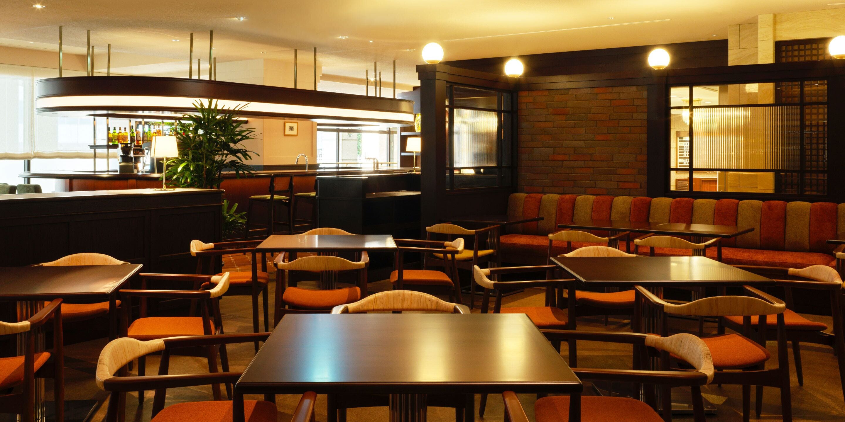 A restaurant with multiple tables and booths, a bar area, and a seating area with cushioned benches.