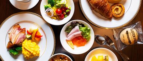 Una mesa con diferentes opciones de desayuno, como cruasanes, huevos y frutas.