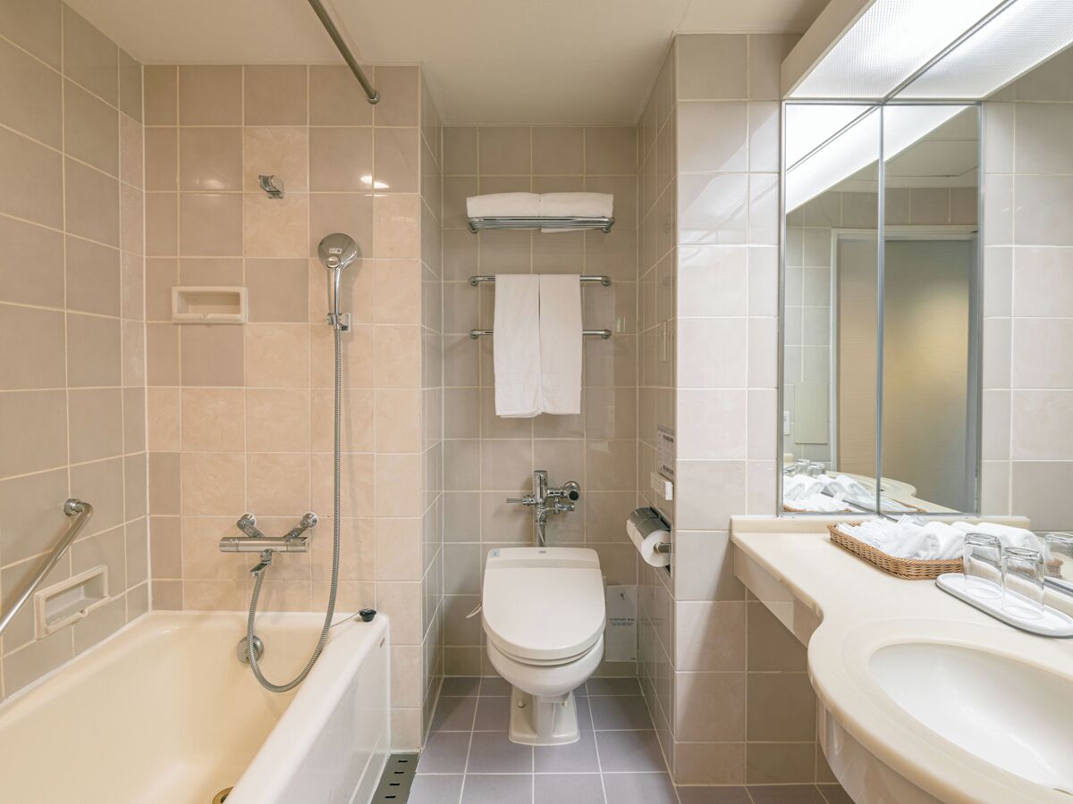 A bathroom with a bathtub, toilet, and sink, all with white fixtures and beige tiles.