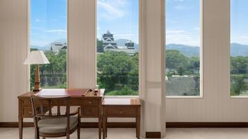 A room with a desk and chair, large windows with a view of traditional Japanese architecture.