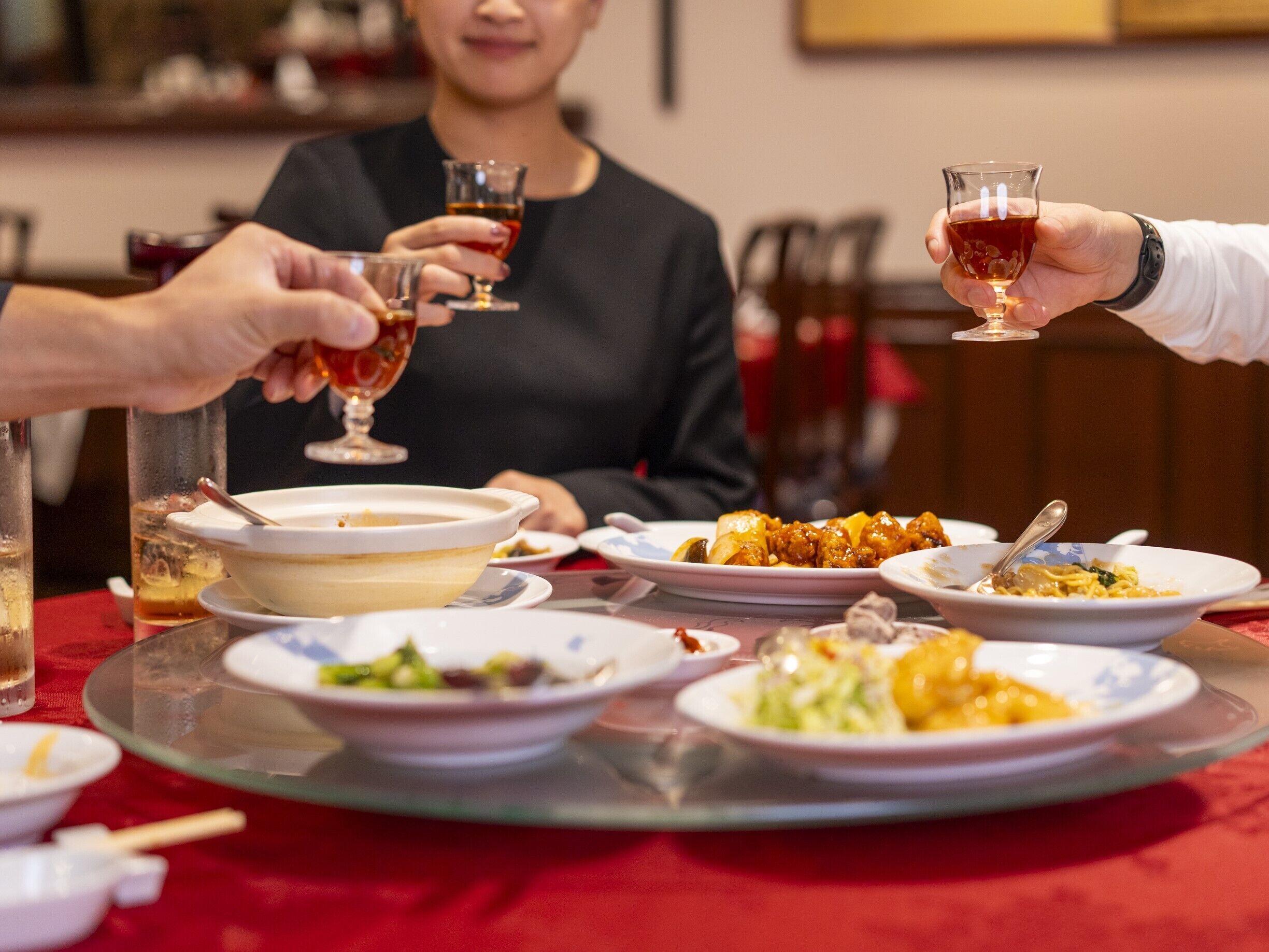 A dining table with various dishes and glasses of red wine.