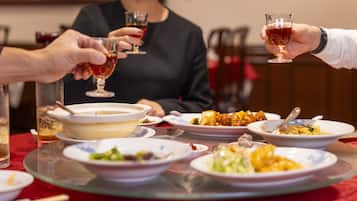 A dining table with various dishes and glasses of red wine.