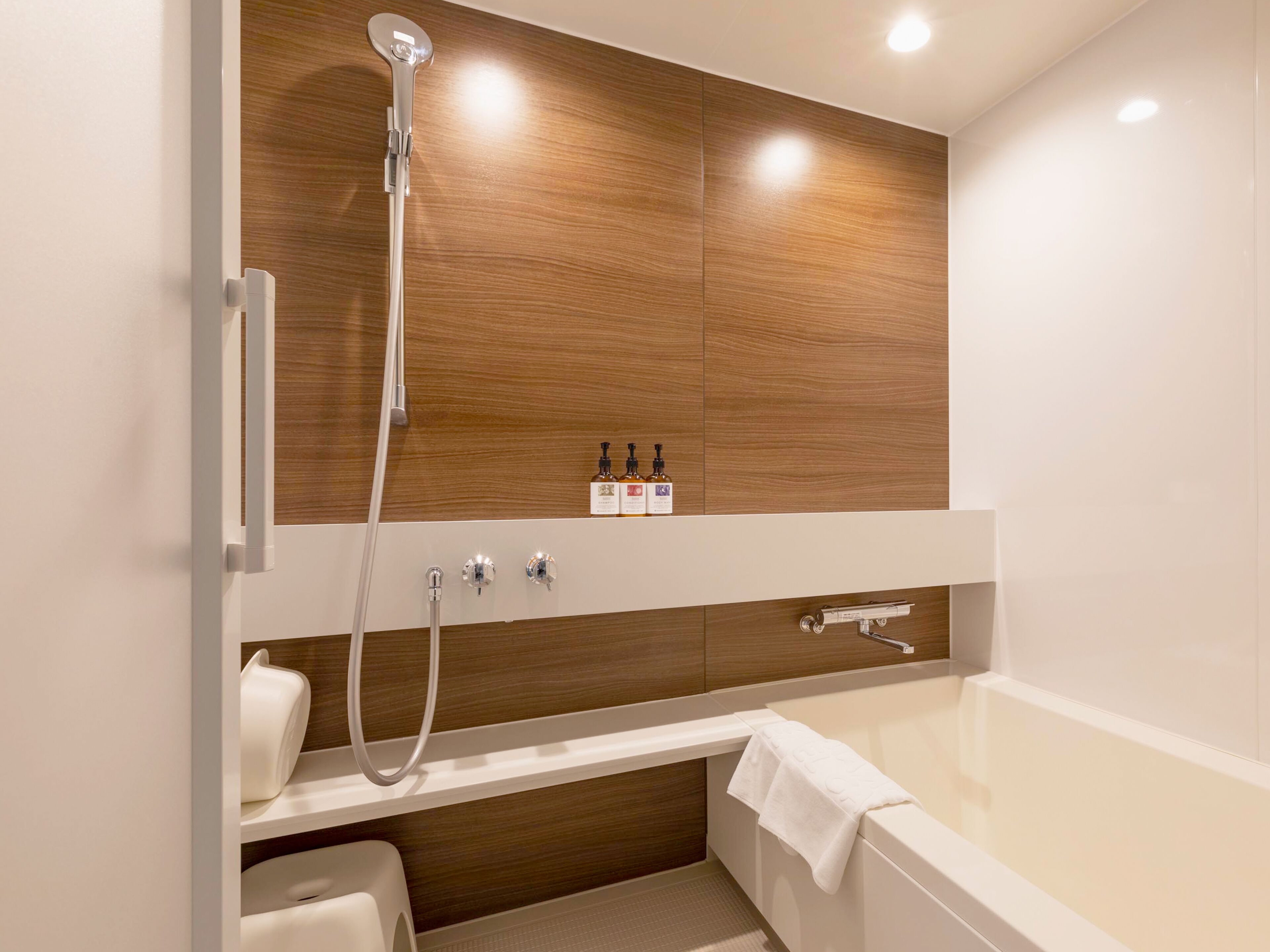 A modern bathroom with a wooden vanity, a bathtub, and a showerhead.