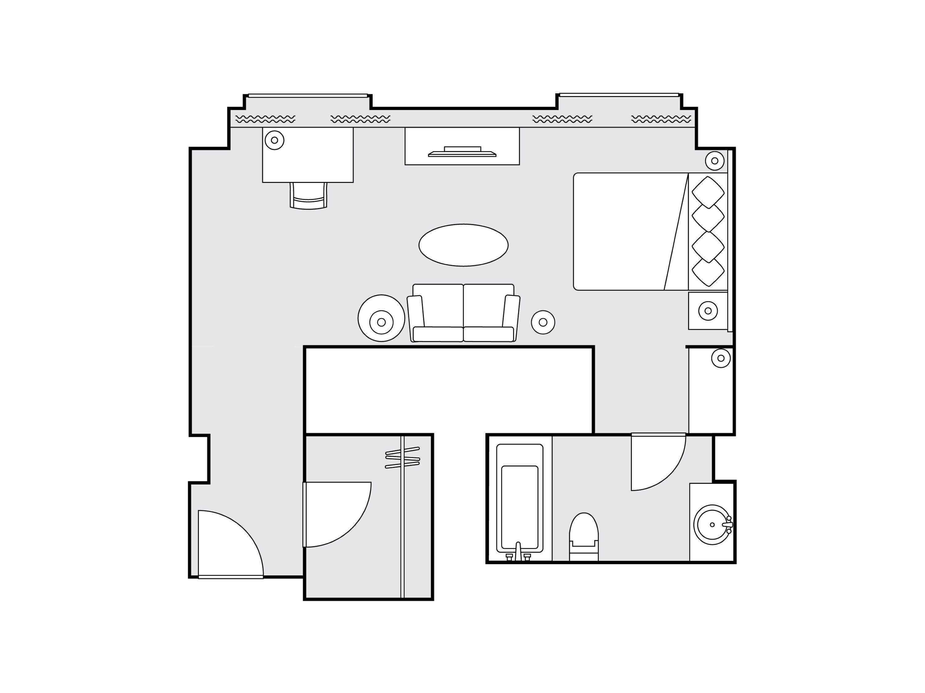 A hotel room layout with a bed, a desk, a chair, a small table, and a bathroom.