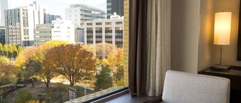 Une chambre d’hôtel avec vue sur les arbres aux couleurs automnales et les bâtiments de la ville.