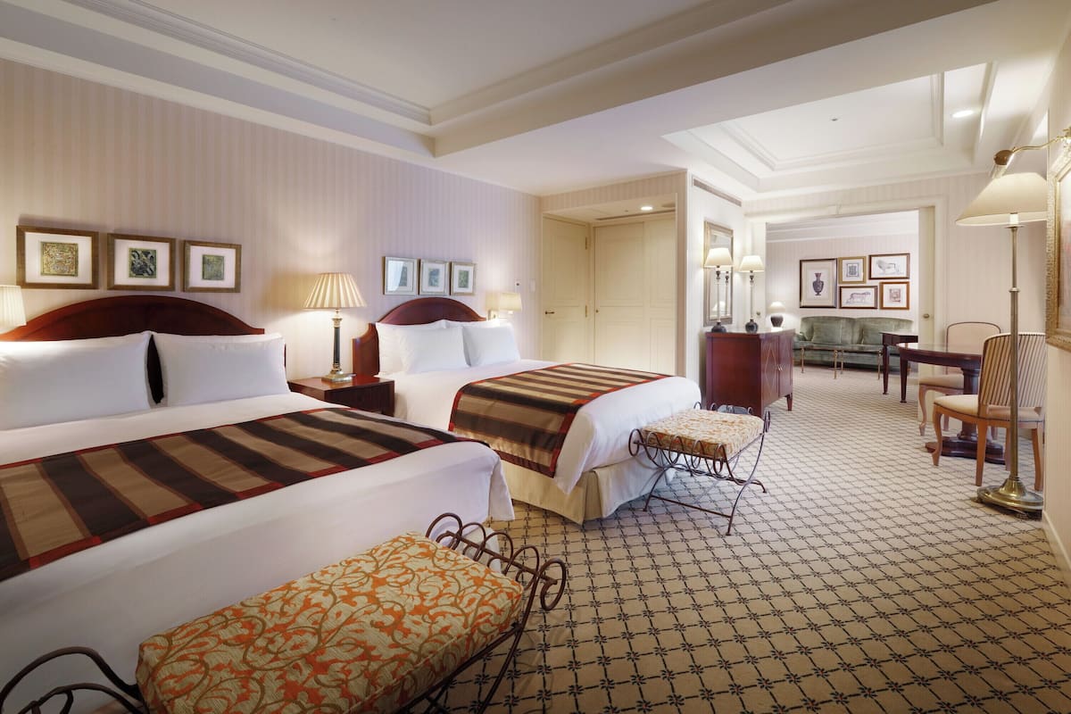 Une chambre d’hôtel avec deux lits, un bureau, une chaise et un canapé.