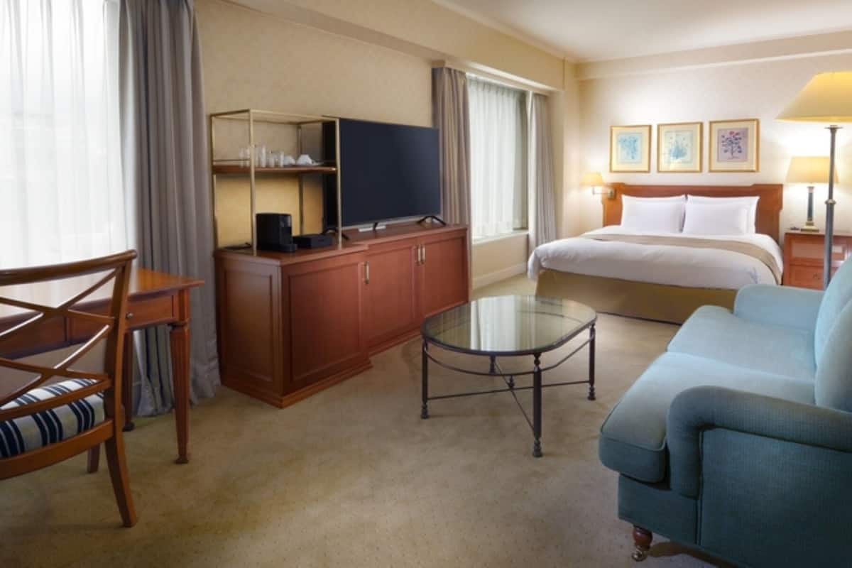 Une chambre d’hôtel équipée d’un lit, d’un canapé, d’un bureau, d’une télévision et d’une machine à café.