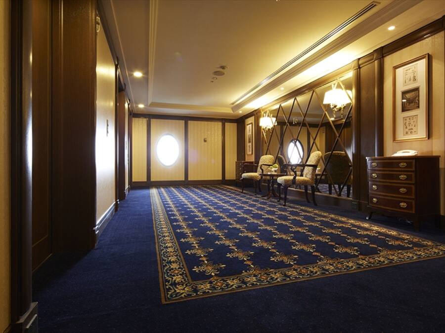 A hotel room with a blue carpet, wooden furniture, and a chandelier.