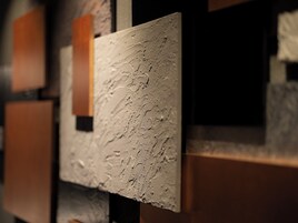 A textured wall with rectangular panels, some with visible indentations.