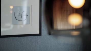 A framed artwork with a simple line drawing on a textured grey wall.