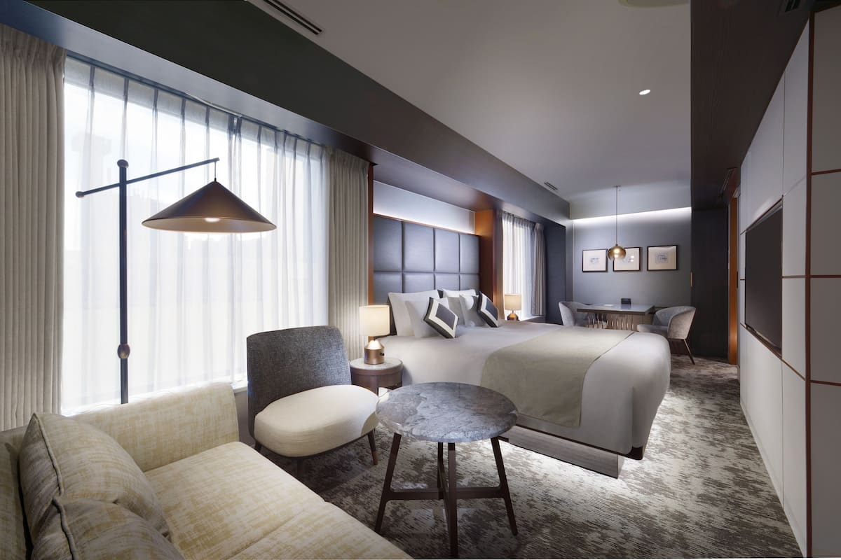 Une chambre d’hôtel avec un grand lit, un canapé, une petite table ronde et un bureau avec une chaise.