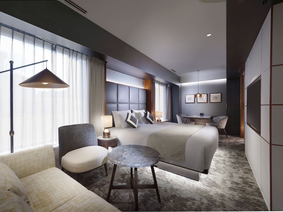 Una habitación de hotel con una cama grande, un sofá, una mesita redonda y un escritorio con una silla.
