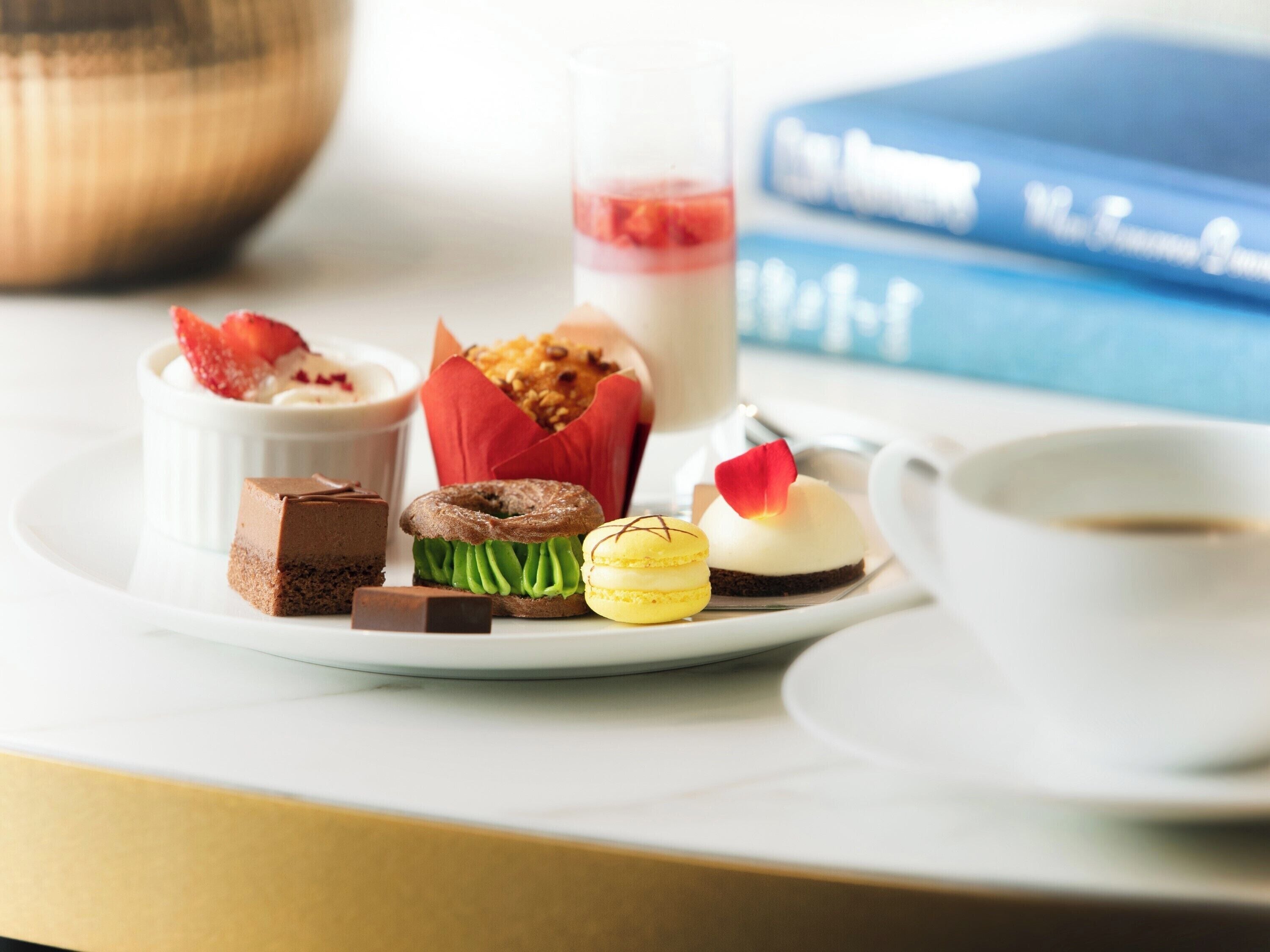 A dessert tray with various pastries and a cup of coffee on a table.