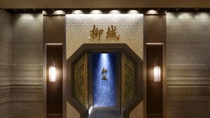 A hotel entrance with a blue door, a textured wall with gold lettering, and two wall-mounted lights. - Nagoya Kanko Hotel (Nagoya)