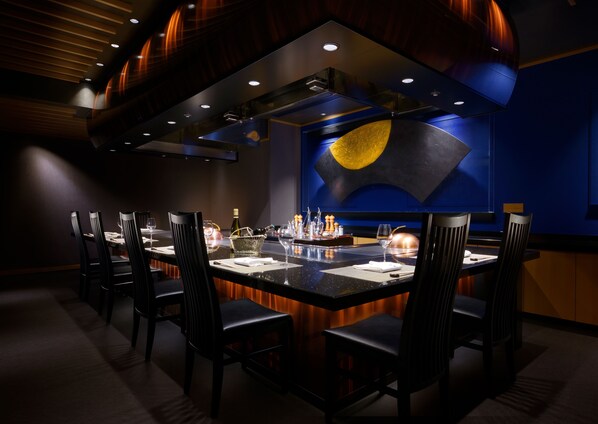 A restaurant with a central island, black chairs, and a blue wall with a circular design.