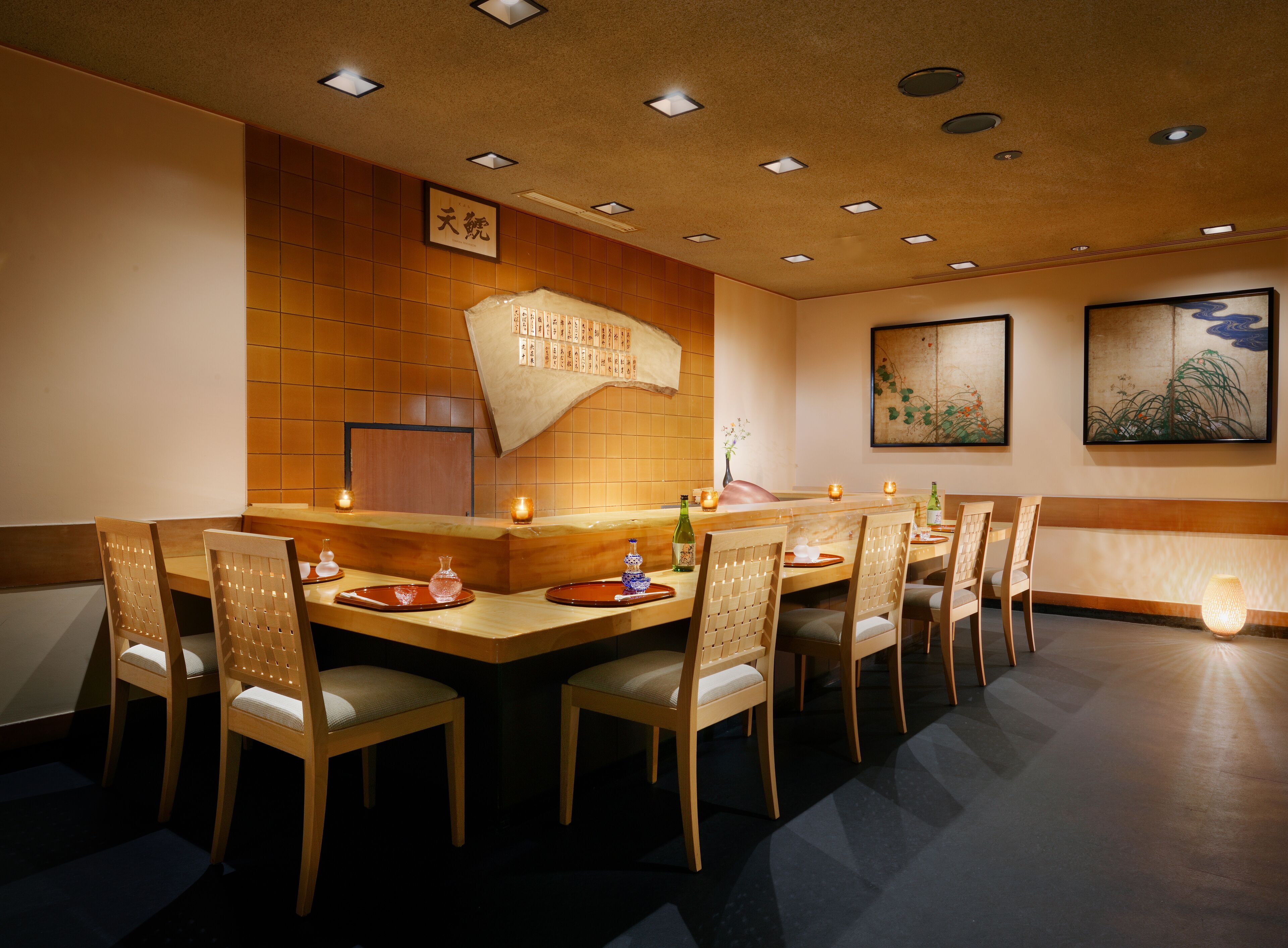 Un restaurante con una larga mesa de madera, varias sillas y un revoque de azulejos.