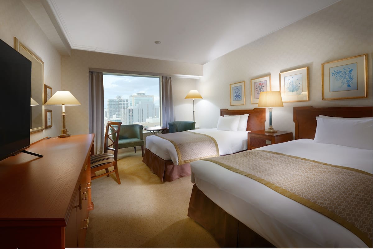 Une chambre d’hôtel avec deux lits, un bureau, une chaise et une télévision.