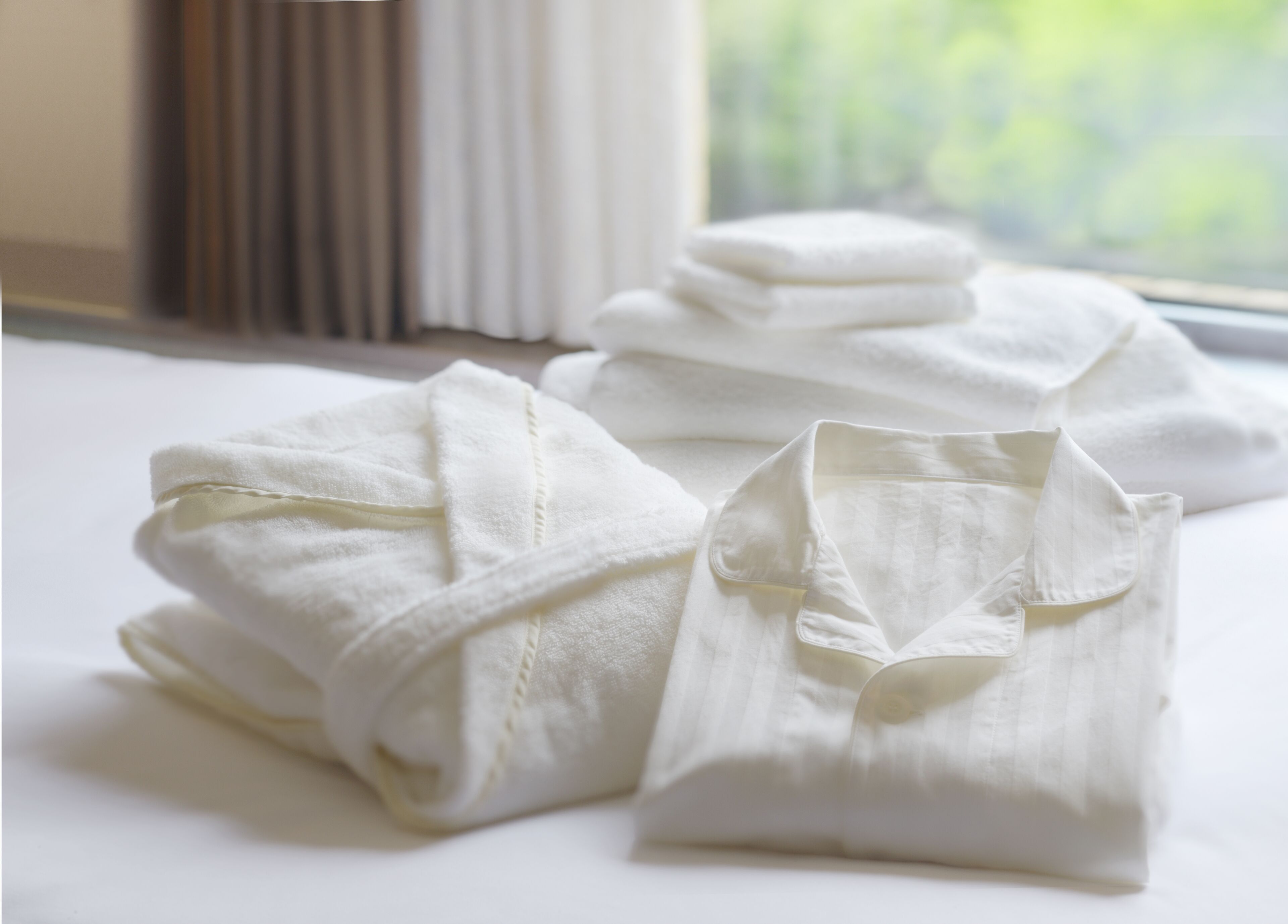 Neatly folded white robes on a bed near a window.