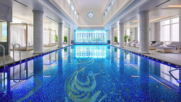A large indoor swimming pool with a tiled floor, surrounded by columns and seating areas. - Nagoya Kanko Hotel (Nagoya)