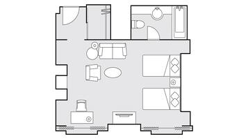 A floor plan of a hotel room with a bed, a desk, a chair, a sofa, a small table, and a bathroom with a toilet and sink.