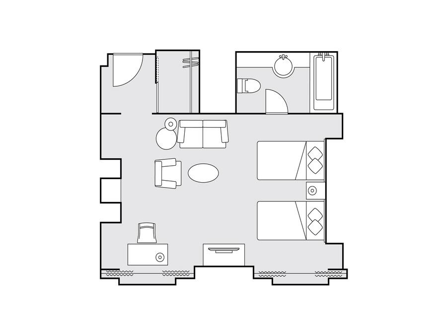 Grundriss eines Hotelzimmers mit Bett, Schreibtisch, Stuhl, Sofa, kleinem Tisch und einem Badezimmer mit Toilette und Waschbecken.