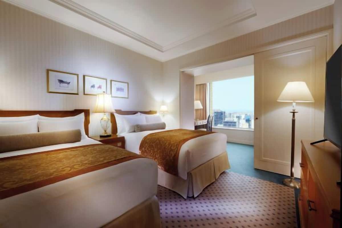 Une chambre d’hôtel avec deux lits, une vue sur la ville et une télévision.