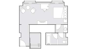 A floor plan of a hotel room with a bed, a desk, a chair, a small bathroom, and a seating area.