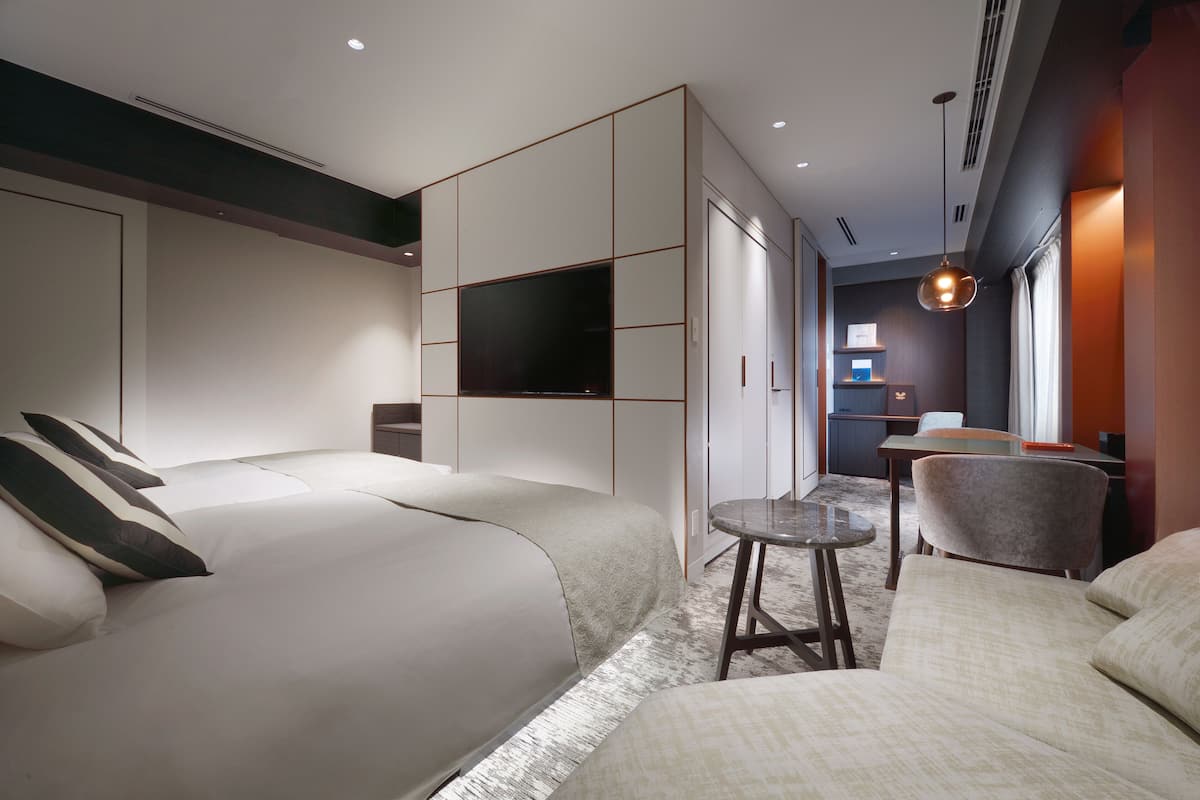 Une chambre d’hôtel moderne avec un grand lit, un coin salon, une télévision et une petite table.
