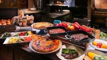 Un buffet con diversi piatti, tra cui pizze, insalate e carni.