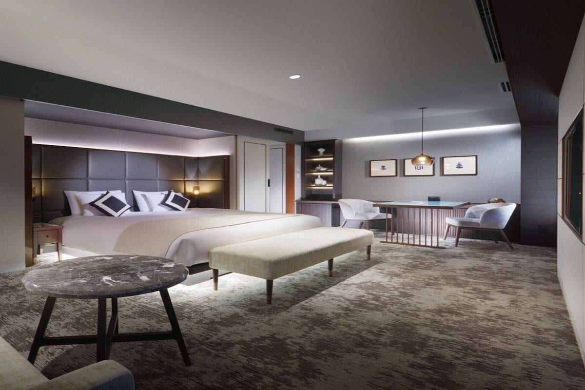 Une chambre d’hôtel moderne avec un grand lit, un petit bureau, une chaise, une table ronde et un canapé.
