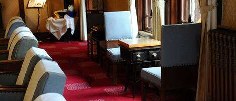Une chambre d’hôtel avec un tapis rouge, une table à manger et plusieurs chaises.