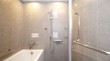 A modern bathroom with a bathtub, shower, and handrails.
