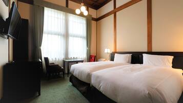A hotel room with a large bed, a desk, a chair, a television, and a lamp.