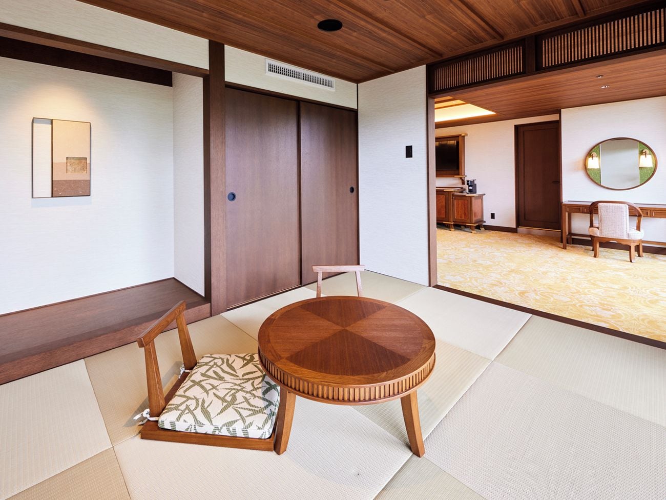 A traditional Japanese room with tatami flooring, a round wooden table, and a low wooden cabinet.