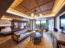 Habitación de hotel con techo de madera, un sofá, una mesa de comedor, televisión y balcón con vistas.