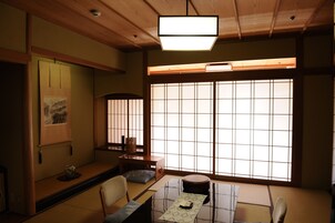 Una habitación tradicional japonesa con suelo de tatami, una mesa baja, un banco acolchado y puertas correderas shoji.