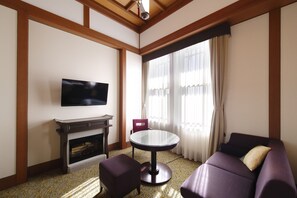 A living room with a fireplace, a television, a round table, and a purple sofa.