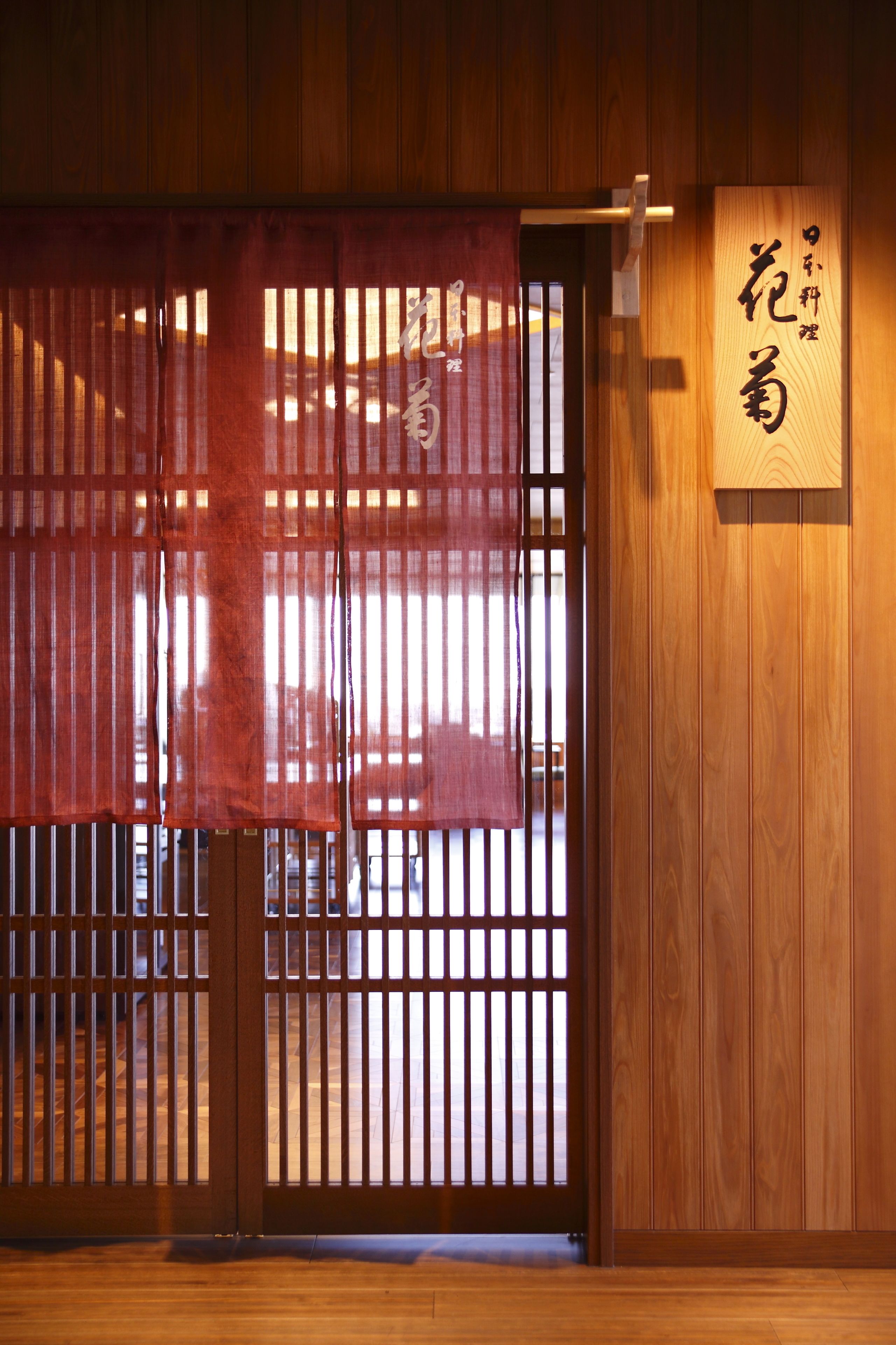 Una habitación tradicional japonesa con puertas correderas de madera, suelo de esteras de tatami y un cartel con caracteres japoneses.