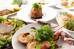 Diversos pratos, incluindo lagosta, bife e uma sobremesa, sobre uma mesa.