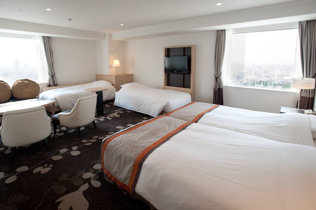 A hotel room with two beds, a desk, and a chair.