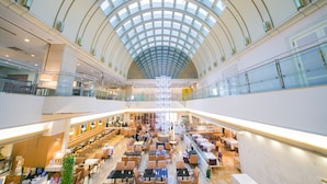 A spacious atrium with a high glass ceiling, multiple dining areas, and a central decorative light fixture. - Hotel Granvia Osaka (Osaka)