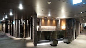 A modern reception area with a reception desk, seating, and a stone accent wall. - Hotel Granvia Osaka (Osaka)