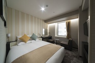 Une chambre d’hôtel avec un grand lit, une table de chevet, un bureau, une chaise et un téléviseur.