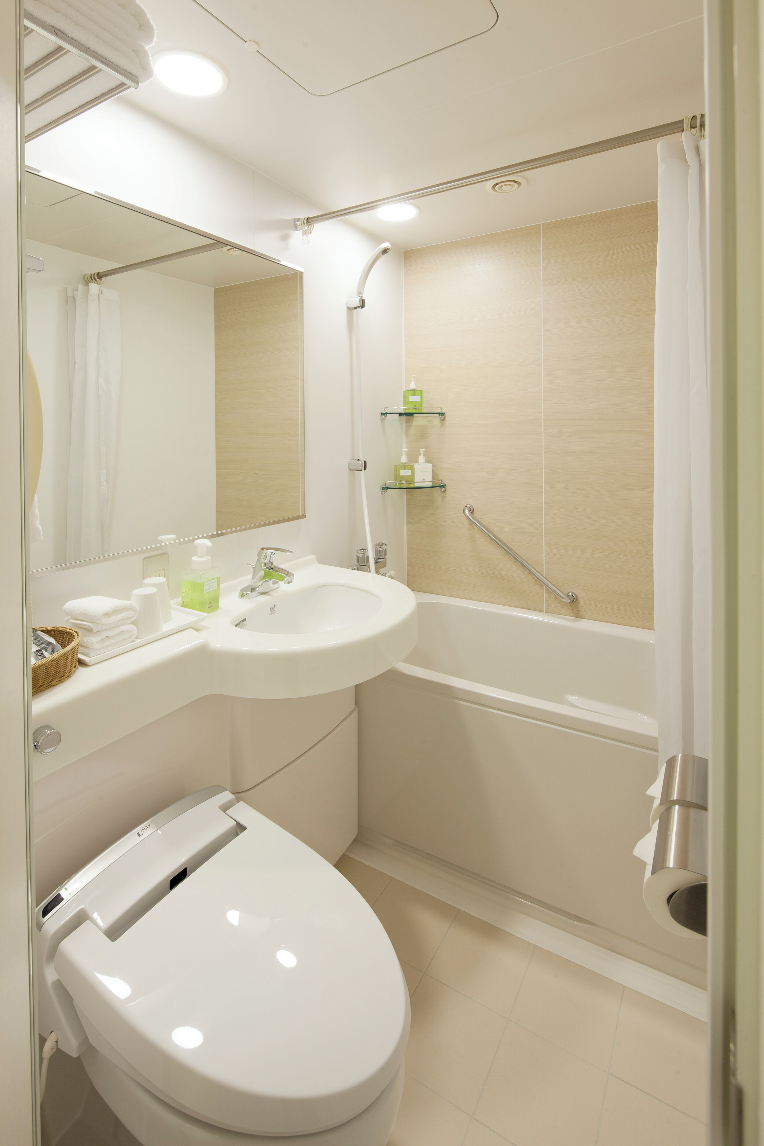 A modern bathroom with a white sink, toilet, and bathtub. There is a mirror above the sink, and a shower curtain is visible in the background.