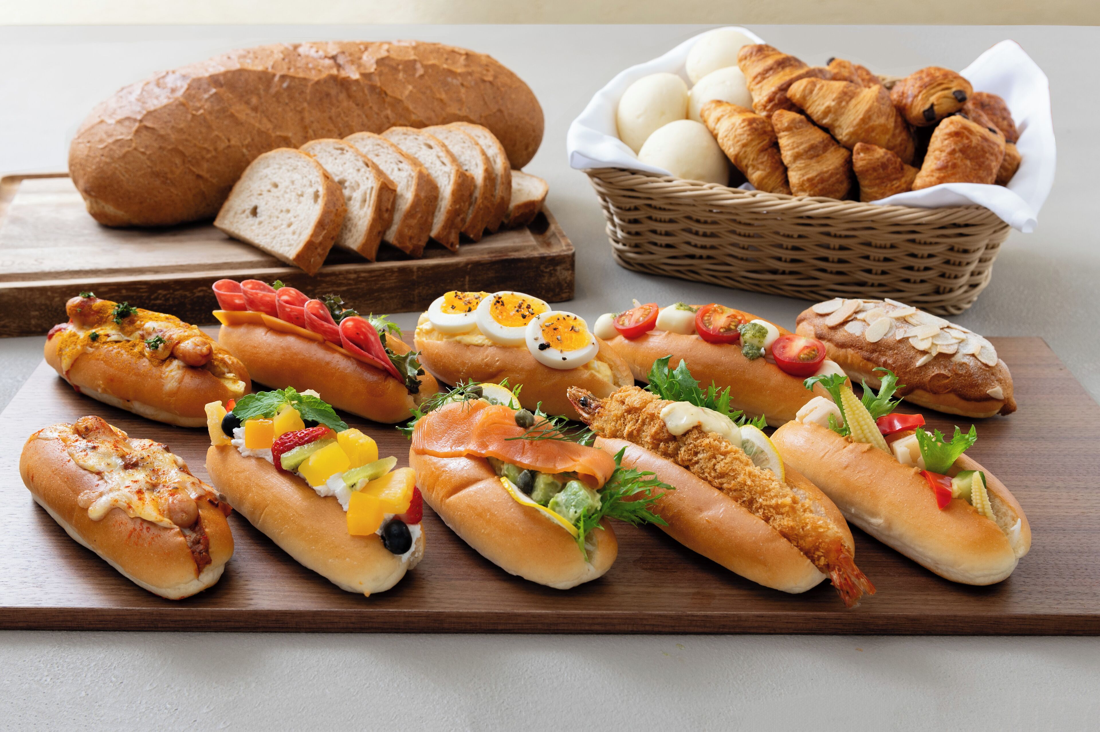 A variety of sandwiches and bread on a wooden board.