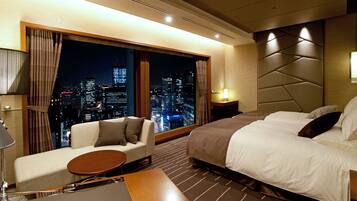 A hotel room with a city view, a sofa, a bed, and a small table.