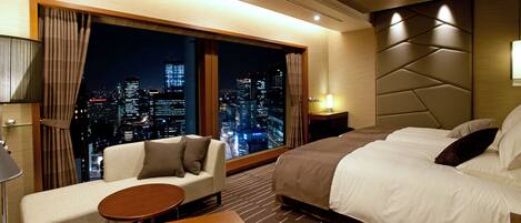 Habitación de hotel con vista a la ciudad, un sofá, una cama y una pequeña mesa.