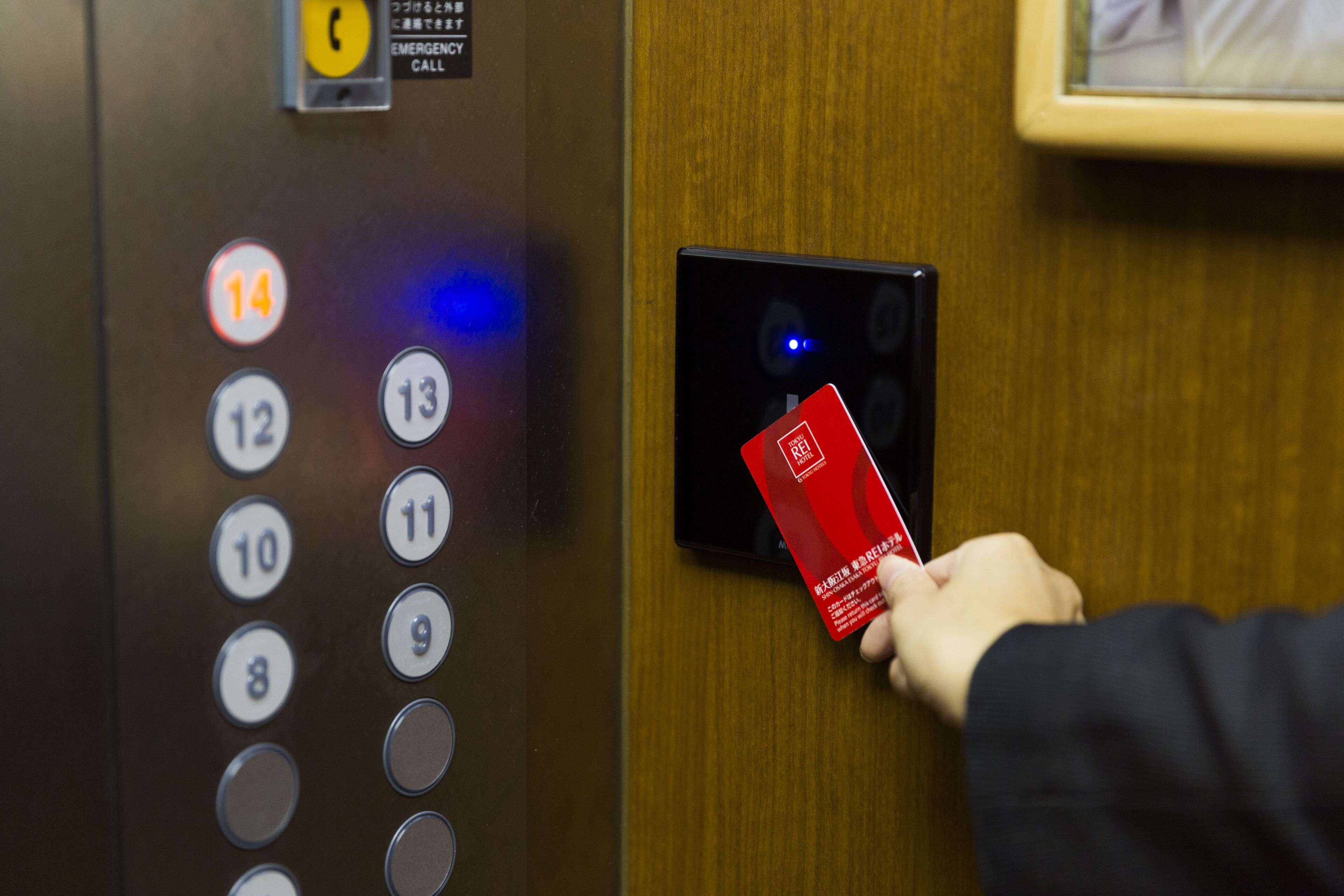 A hand inserting a red card into an elevator card reader.